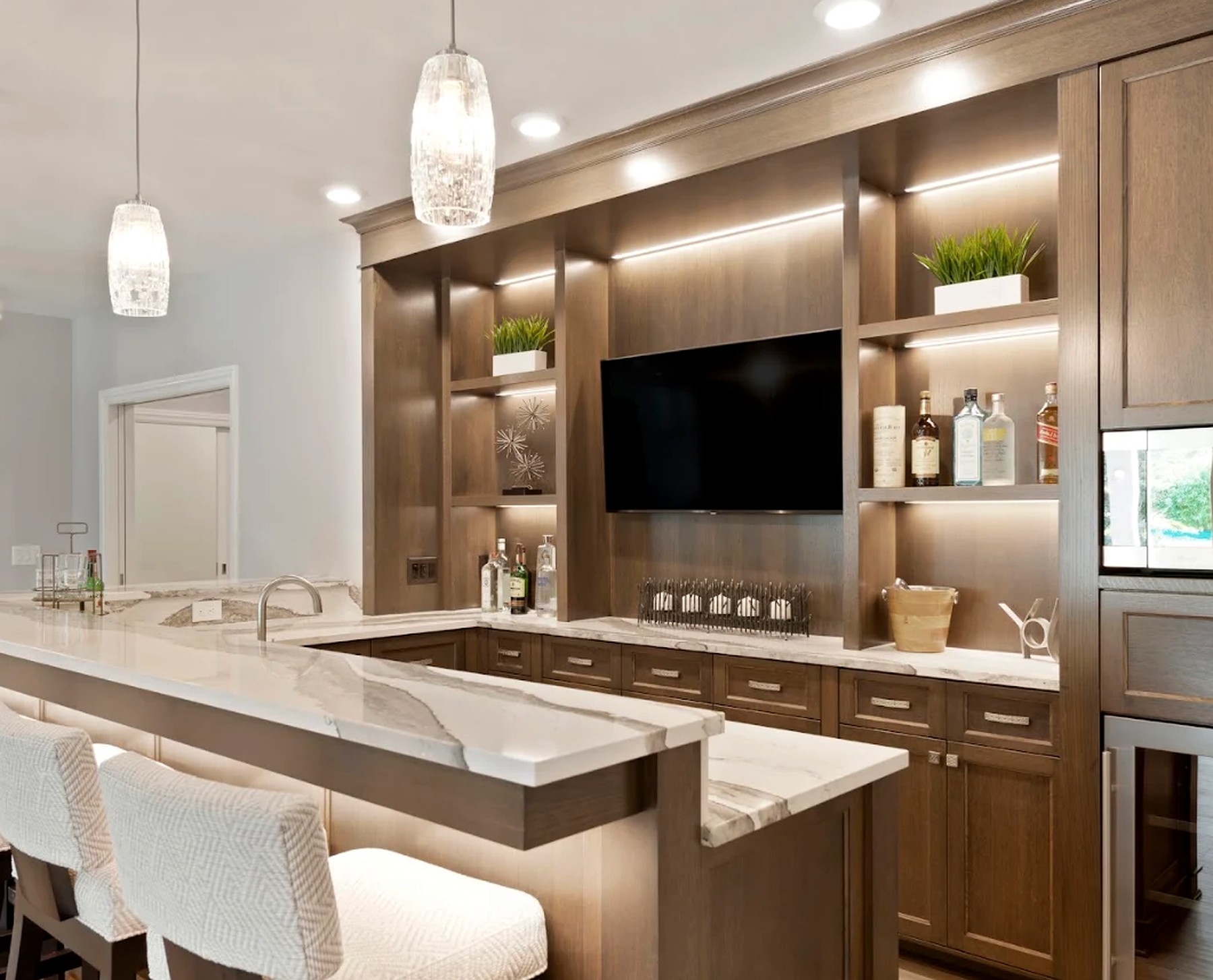 Lower level wet bar with marble counters, lit walnut shelving and upholstered stools